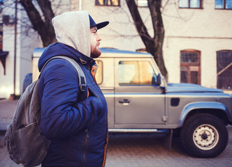 Portrait of traveller man with bag near car outdoor in city street