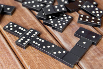 Black old, vintage dominoes on a wooden table closeup. The concept of the game dominoes.