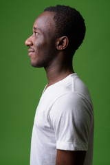 Profile view portrait of young African man against green background