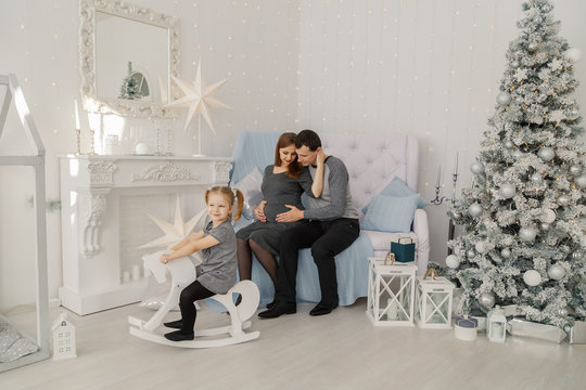 Happy and beautiful family of three at a festive bright New Year's room.