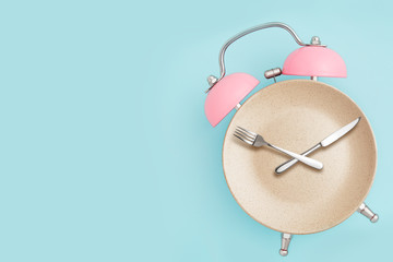 Alarm clock and plate with cutlery . Concept of intermittent fasting, lunchtime, diet and weight...