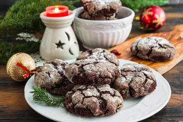 Cracked chocolate cookies with cranberries on white plate on wooden rustic table. Christmas decoration