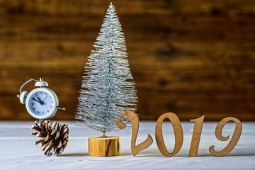 New Year's composition: a clock and a Christmas tree on a wooden background.