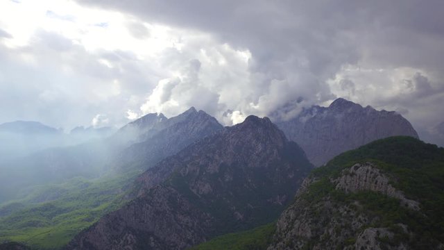 Beautiful cloudy landscape of high mountains, grey clouds, shiny sea water and sun rays falling down on earth through clouds. Turkey. Real time 4k video footage.