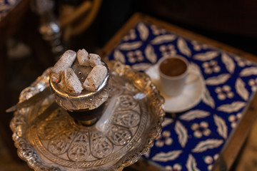 Hookah with coconut charcoal for relax and shisha smoke. Hot coals with hookah sparks in metal bowl for  Smoking and traditional Asian relaxation close up. hookah and coffee from the top close up view
