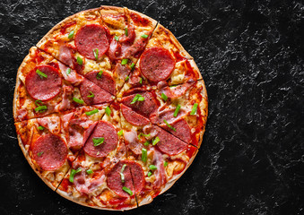 Pepperoni Pizza with Mozzarella cheese, salami, bacon, Tomato sauce, pepper, Spices and Fresh green onion. Italian pizza on black background