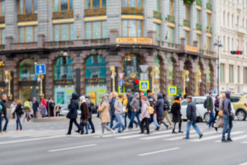 Fototapeta na wymiar in the blur of the intersection where a group of people cross the street on the background of the building