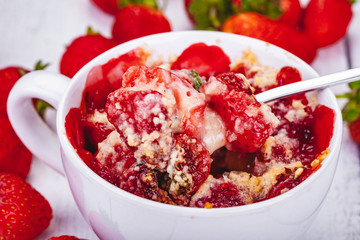 Strawberry crumble in cup on wooden rustic table. Close up