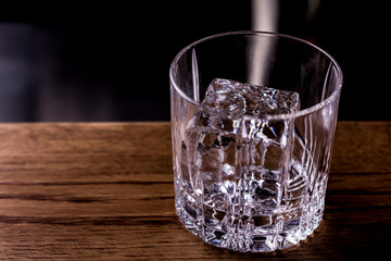 Bartender making refreshing coctail on a bar background. Dark moody style. Ice in tha glass