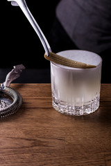 Bartender making refreshing coctail on a bar background. Dark moody style. Ice in tha glass