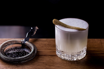 Bartender making refreshing coctail on a bar background. Dark moody style. Ice in tha glass