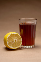 A glass of strong tea with lemon on a brown background