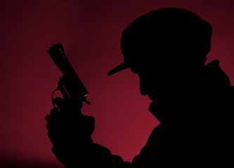 side view silhouette of man with a gun in the darkness