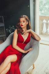 Hot young adult and imperious woman, dressed in a long scarlet red long dress, sexually shows her...