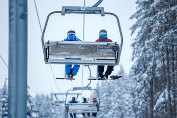 People with ski lifting on ski-lift in mountains