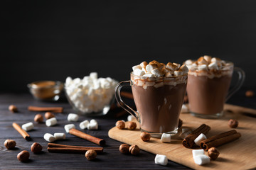 Hot drinks with marshmallows on cutting board between cinnamon