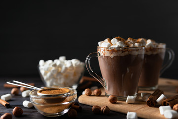 Hot drinks with marshmallows on cutting board between cinnamon