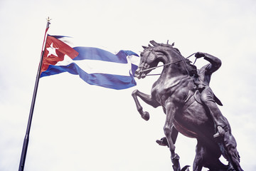 Statue of a cuban horse rider in front of the Cuban national flag symbolizing the fight for freedom...