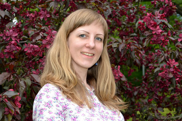 The joyful young woman against the background of the blossoming Royalty grade apple-tree