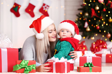 Fototapeta na wymiar Mother and son in santa hats celebrate christmas at home