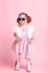 Beautiful little girl in fashion clothes on pink background