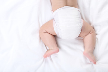 Little boy in diaper lying on white bed