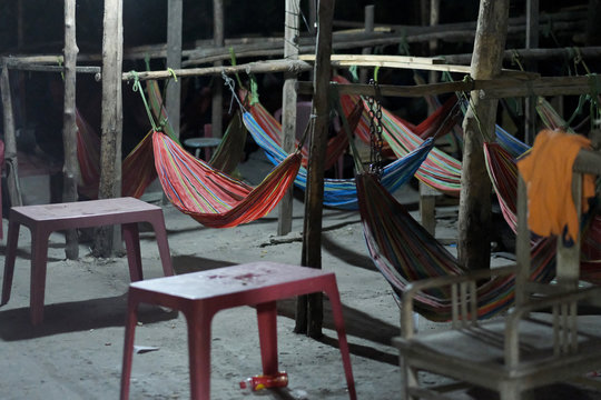 A place to sleep in a barn with hammocks tied to the crossbar between the pillars.
