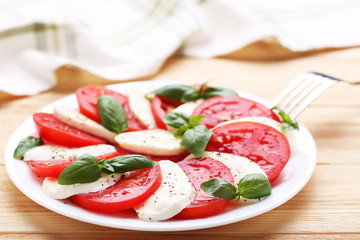 Mozzarella, tomatoes and basil leafs on brown wooden table