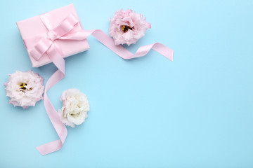 Gift box with ribbon and eustoma flowers on blue background