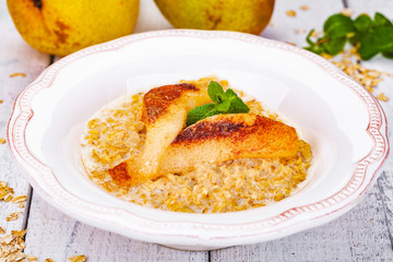 Oatmeal porridge with pear in white plate. Close up