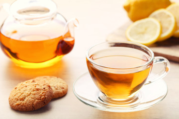 Cup of tea with cookies and teapot on wooden table