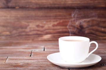 Cup of tea with steam on brown wooden table