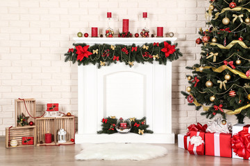 White decorated fireplace near christmas tree on brick wall background