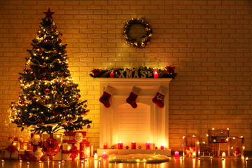 White decorated fireplace near christmas tree on brick wall background