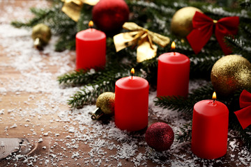 Christmas candles with fir-tree branches and baubles on wooden table