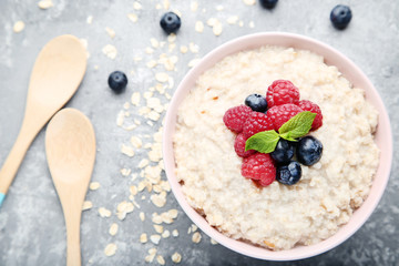 Oatmeal with berries in bowl on grey wooden table