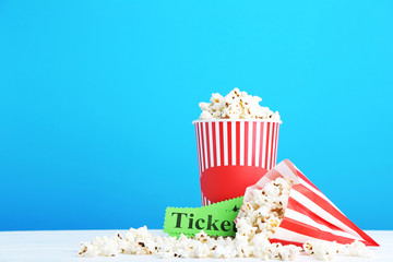 Popcorn in striped bucket and paper bag on blue background