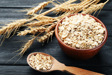 Oatmeal in bowl and spoon on black wooden table