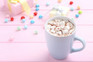 Cappuccino with marshmallows in cup and paper stars on pink wooden table