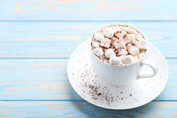 Cappuccino with marshmallows in cup on blue wooden table