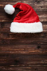 Obraz na płótnie Canvas Santa claus hat on brown wooden table