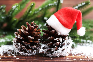 Cones with santa claus hat and fir tree branches on wooden table © 5second