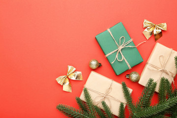 Christmas fir tree branches with gift boxes on red background