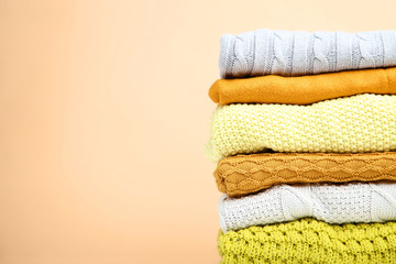 Stack of folded sweaters on beige background