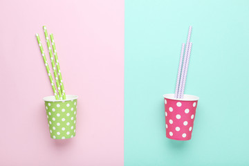 Pink and green paper cups with straws on colorful background