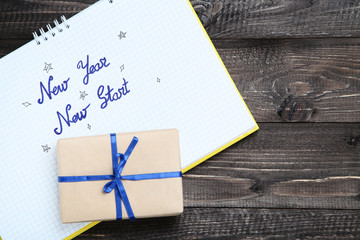 New year new start in notepad with gift box on wooden table