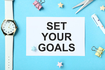 Fototapeta na wymiar Set your goals on sheet of paper with wrist watch, clips and colorful stars