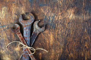 Metal bunch wrench rusty tools lying on dark wooden table tied with rough rope bouquet for real man