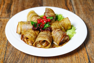 eggplant rolls stuffed with meat with lettuce and berries on wooden background