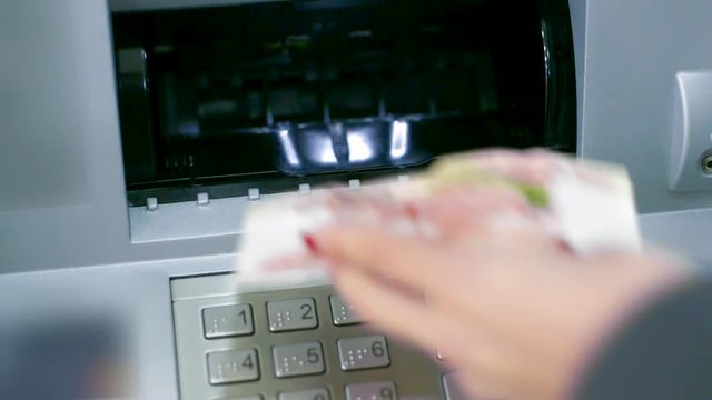 closeup ATM slot cover opens woman puts banknote backwards